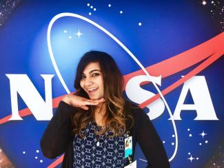 Debarati Das standing in front of the NASA meatball logo