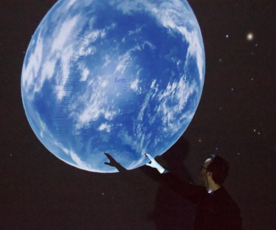 Trevor pointing at Earth in the planetarium