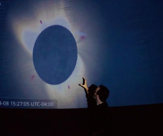 Trevor pointing at solar eclipse in planetarium dome